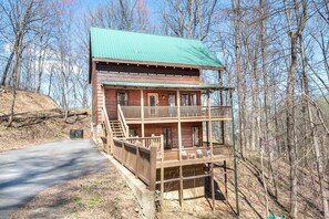A wooden cabin with a green roof, a balcony, and a staircase leading to the upper level. - Smoky Summit Stays (Sevierville)