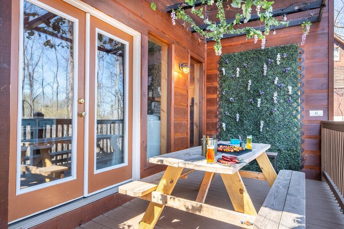 A wooden deck with a picnic table, a glass door, and a wall covered in greenery.