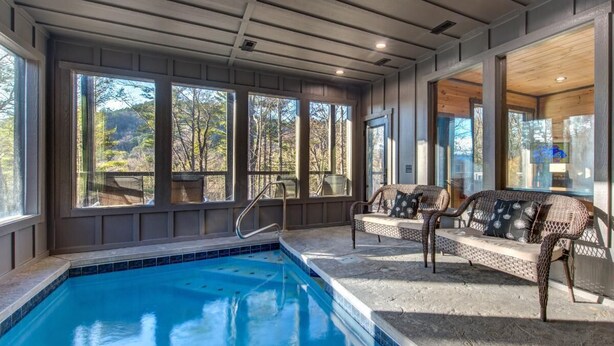 A pool area with a view of trees, a sofa, and a chair. - Bearfoot Splash Hideaway (Sevierville)