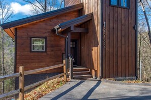 A wooden cabin with a number '2982' on the door, a small window, and a wooden staircase leading to the entrance. - Bearfoot Splash Hideaway (Sevierville)
