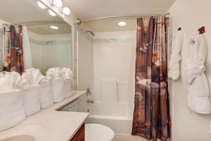 A bathroom with a shower, a toilet, a sink, and a mirror. There are towels and a robe rack. - Cs Creekside Condo (Gatlinburg)