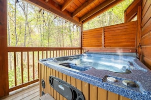 A hot tub in a wooden cabin with a view of a forest. - Roudys Roost (Pigeon Forge)