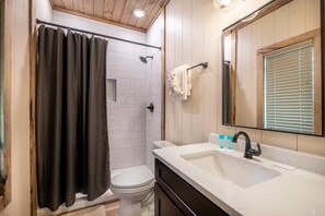 Ein Badezimmer mit Dusche, Toilette, Waschbecken und Spiegel.