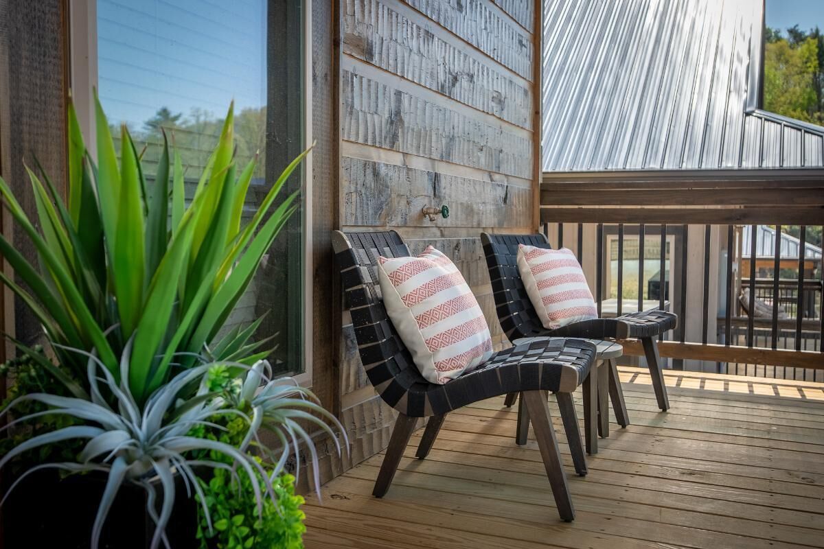 A wooden deck with two chairs and a potted plant.