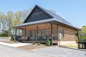 Eine Holzhütte mit geneigtem Dach, einer Veranda mit Bänken und einem kleinen Garten.