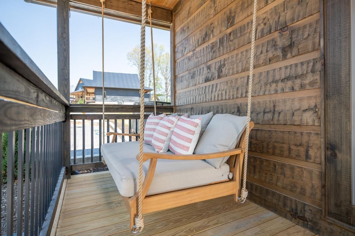 Een houten schommelstoel met kussens op een houten terras.