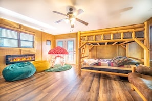 A cozy room with a bunk bed, a fireplace, a ceiling fan, and a window with blinds. - Birdies and Bearcubs (Pigeon Forge)