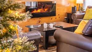 A cozy living room with a fireplace, leather furniture, and a Christmas tree. - Birdies and Bearcubs (Pigeon Forge)
