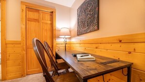 A wooden-paneled room with a table, chairs, a lamp, and a door. - Z - Bear Ridge (Gatlinburg)