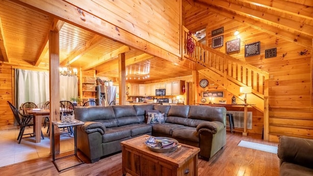 A log cabin interior with a living room, dining area, kitchen, and staircase. - Timber Tails (Sevierville)