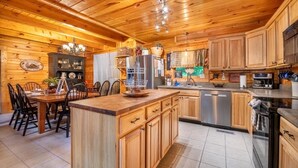 A wooden interior with a kitchen, dining area, and a small island with a sink. - Timber Tails (Sevierville)