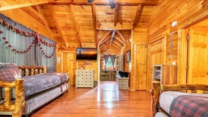 A log cabin interior with a wooden floor, two sofas, a television, and a fireplace. - Timber Tails (Sevierville)