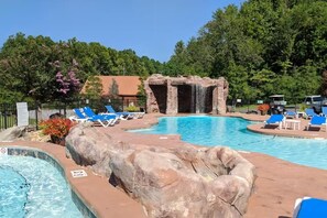 Ein Swimmingpool mit Wasserfall, Liegestühlen und einer natürlichen Kulisse.