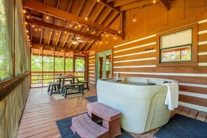 A wooden cabin with a hot tub, wooden deck, and a table with benches. - Haus Edelweiss (Sevierville)