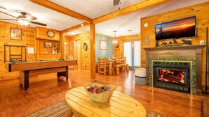 Un intérieur en bois avec une table de billard, une cheminée et un téléviseur.