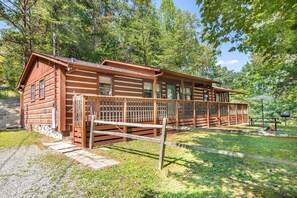 A log cabin with a porch, surrounded by trees. - Haus Edelweiss (Sevierville)