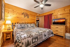 A wooden cabin bedroom with a bed, a ceiling fan, a TV, and a wooden dresser. - Haus Edelweiss (Sevierville)