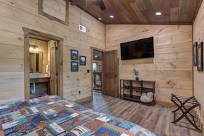 Ein Holzblockhaus-Interieur mit einem Bett, einem Fernseher, einem Waschbecken und gerahmten Bildern an den Wänden.