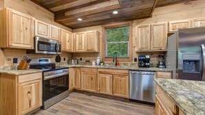Una cocina con armarios de madera, un refrigerador de acero inoxidable, un microondas, un horno y un lavavajillas.