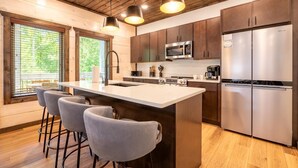 A modern kitchen with a large island, stainless steel appliances, and bar stools. - Smoky Mountain Sapphire (Pigeon Forge)
