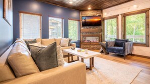 A cozy living room with a stone fireplace, leather sofas, and large windows. - Smoky Mountain Sapphire (Pigeon Forge)