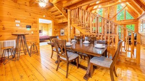 Un intérieur en bois comprenant un coin repas, un escalier et une vue sur l’extérieur.