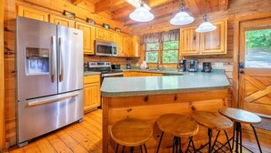 Une cuisine de style rustique, avec des éléments en bois, comprenant un réfrigérateur, un four à micro-ondes et des tabourets de bar.