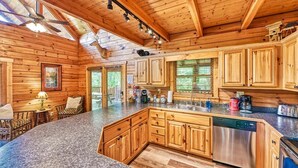 A wooden cabin interior with a kitchen, dining area, and a ceiling fan. - Mountain Song (Gatlinburg)