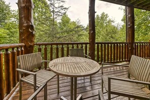 A wooden deck with a round table and four chairs, surrounded by a wooden railing. - Mountain Song (Gatlinburg)