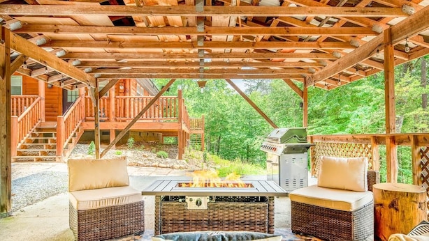 A covered outdoor seating area with a fire pit, wicker furniture, and a wooden deck. - Oldham Ridge Retreat (Sevierville)