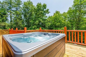 A hot tub on a wooden deck with a wooden railing, surrounded by trees. - Oldham Ridge Retreat (Sevierville)
