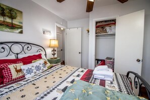A bedroom with a bed, a bedside table, a lamp, a wardrobe, and a painting on the wall. - Hillside Hideaway (Sevierville)