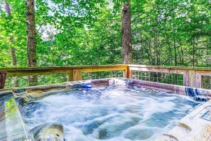 A hot tub surrounded by a wooden deck and trees. - Hillside Hideaway (Sevierville)