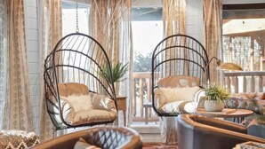 A room with hanging chairs, a sofa, a small table with a plant, and curtains. - Smoky Fox Lodge (Sevierville)