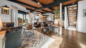 A spacious living area with a high ceiling, wooden beams, a staircase, and a view of the outdoors. - Smoky Fox Lodge (Sevierville)