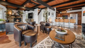 A spacious living area with leather sofas, a fireplace, a dining table, and a kitchen in the background. - Smoky Fox Lodge (Sevierville)
