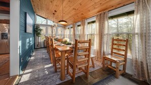A dining area with wooden tables and chairs, large windows with curtains, and a wooden ceiling. - Smoky Fox Lodge (Sevierville)