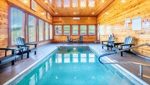 Ein Hallenbad mit Holzwänden und -decke, umgeben von Stühlen und Tischen.