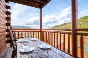 A wooden deck with a table set for dining, overlooking a mountainous landscape. - Splash Mountain Lodge (Sevierville)