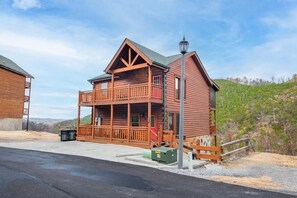 A log cabin with a balcony, a porch, and a street lamp. - Splash Mountain Lodge (Sevierville)