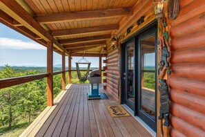 A wooden deck with a hanging chair, a grill, and a view of the landscape. - Lakeview Serenity (Sevierville)