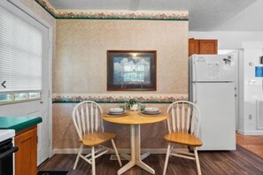 A kitchen with a dining table, chairs, a refrigerator, and a framed picture on the wall. - Mountain Dew (Gatlinburg)