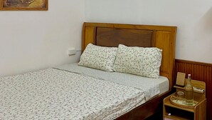 A single bed with floral bedding, a wooden headboard, a nightstand with a bottle, and a framed picture on the wall. - Cozy Room in the Quiet Space of Hue (Thành phố Huế)