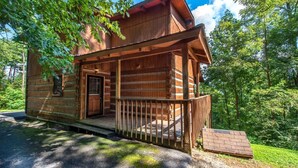 A wooden cabin with a porch, a door, and a small ramp leading to the entrance. - Paradise (Gatlinburg)