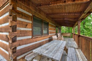 A wooden cabin with a covered porch, a picnic table, and a bench. - Paradise (Gatlinburg)