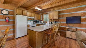 A wooden cabin interior with a kitchen, dining area, and a TV. - Paradise (Gatlinburg)