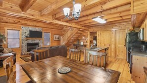 Ein Holzblockhaus-Interieur mit Essbereich, Kamin, Küche und Treppe.