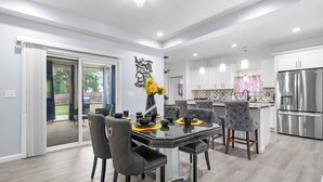 Cocina moderna con comedor, que incluye una isla grande, electrodomésticos de acero inoxidable y vistas al exterior.