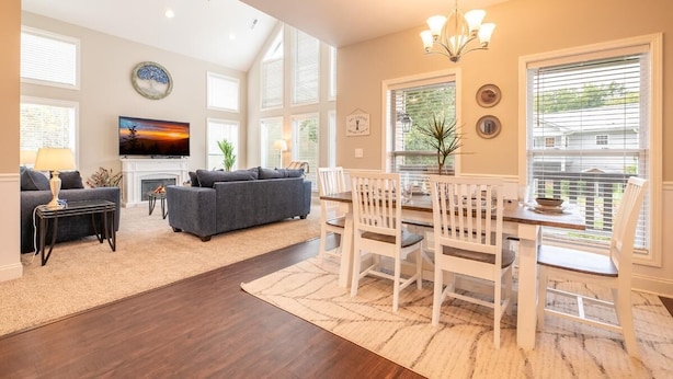 A spacious living room with a fireplace, a dining area with a chandelier, and large windows. - Fabulous Farmhouse (Sevierville)