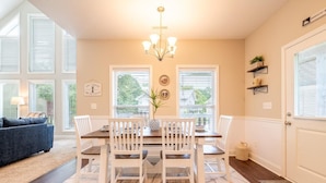 A dining area with a table, chairs, a chandelier, and a view through the windows. - Fabulous Farmhouse (Sevierville)